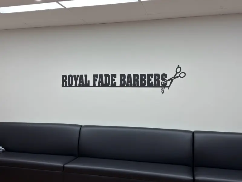 The Royal Fade Barbers sign above the waiting couch inside the shop